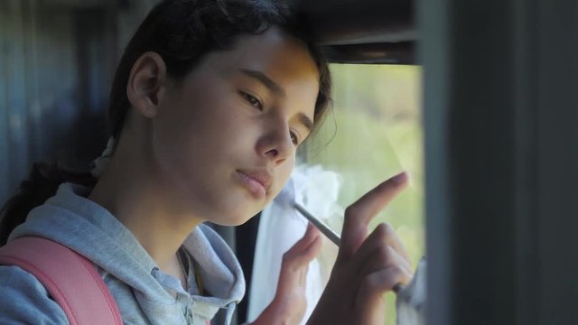 sad girl looks out the train window. travel transportation railroad concept lifestyle . teen girl misses traveling in a train compartment looking out the window. long train journey by rail