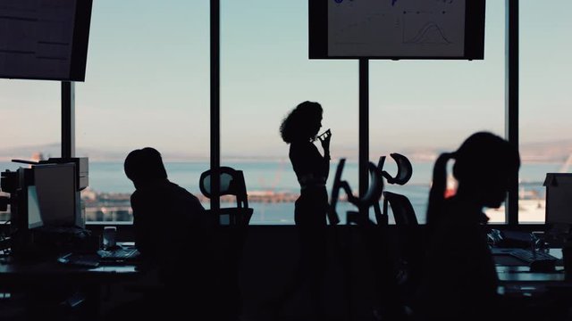 silhouette of business woman using smartphone having phone call chatting on mobile phone looking out window corporate executive discussing sales working late in busy office 