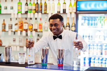 African american bartender working behind the cocktail bar. Alcoholic beverage preparation.