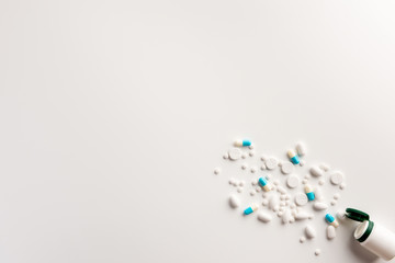 Bottle with scattered pills on white background. Flat lay.