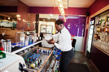 African american bartender at bar with ice bucket. Alcoholic beverage preparation.
