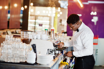African american bartender barista at bar preparing coffee.