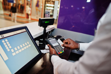 African american bartender at bar uses a credit card terminal on cashier.