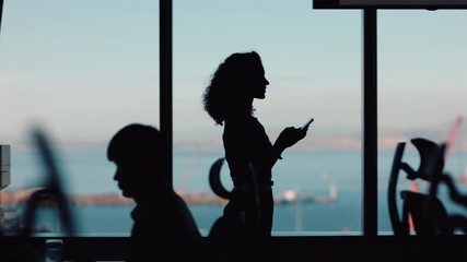 silhouette business woman using smartphone walking through office texting sending messages successful female executive checking emails on mobile phone arriving at workplace - Powered by Adobe