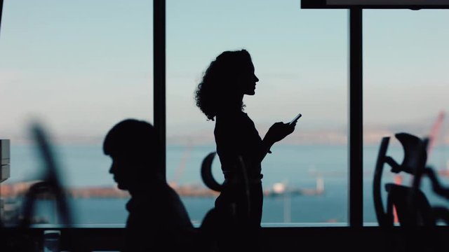 silhouette business woman using smartphone walking through office texting sending messages successful female executive checking emails on mobile phone arriving at workplace