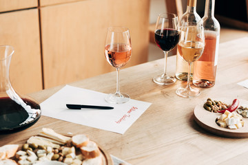 wine tasting document, wine glasses, bottles and food on wooden table