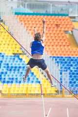 Pole vault - an athletic man jumping over the bar