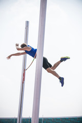 Pole vault - a young athletic man jumping over the bar