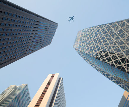 Low angle view of skyscrapers with airplane flying in sky