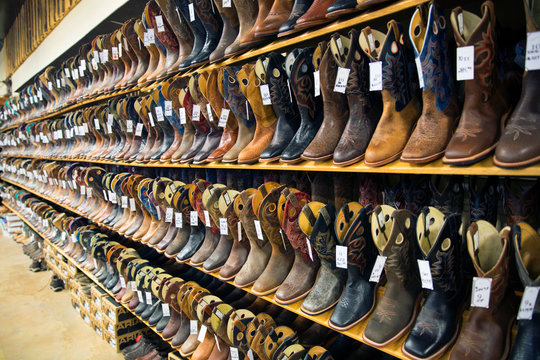 View of brown and black leather cowboy boots on shelves in shop
