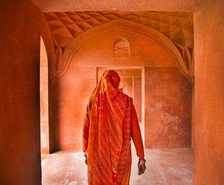 Rear view of woman in orange sari walking in corridor