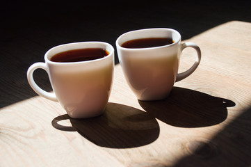 two cups of coffee on wooden background. Beautiful white cups, stylish toning, place for text. Cup of black tea on wooden background. cheerful morning concept