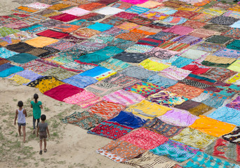 High angle view of children walking in field beside colorful clothes