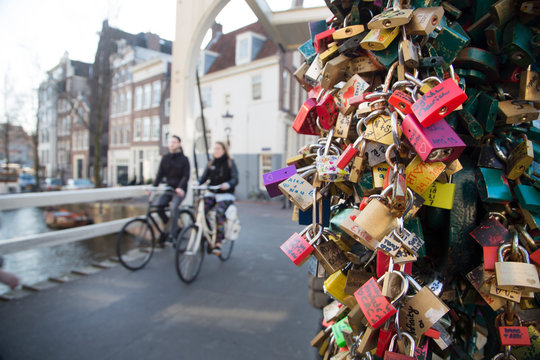 Man and woman riding bicycle by love padlocks