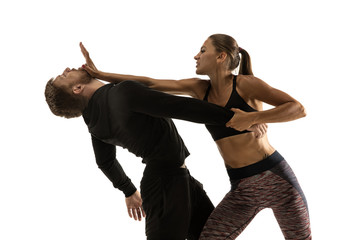 Man in black outfit and athletic caucasian woman fighting on white studio background. Women's...