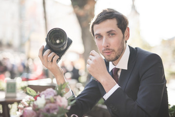 Naklejka premium light photo, men photogapher in suit keep camera in hand