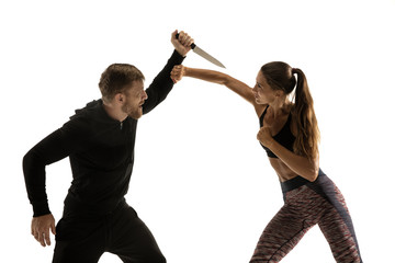 Man in black outfit and athletic caucasian woman fighting on white studio background. Women's...
