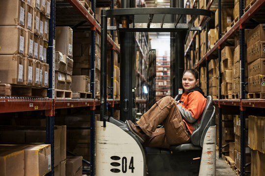 Portrait of woman sitting in stock picker in distribution warehouse