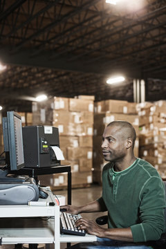 Man working on desktop computer in distribution warehouse