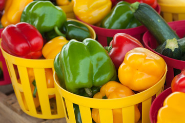 Beautiful and colorful red, green and yellow peppers in plastic baskets at a local farmer's market.