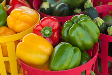 Beautiful and colorful red, green and yellow peppers in plastic baskets at a local farmer's market.