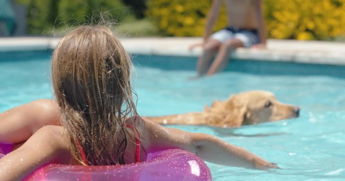 happy little girl in swimming pool floating on swim tube with playful dog having fun with kids enjoying summer day  on vacation 4k