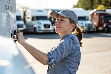 Side view of truck driver getting into truck at truck stop