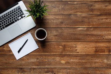 work space of a businessman. view from above . coffee black note and laptop on the desktop with black note. laptop on wooden background