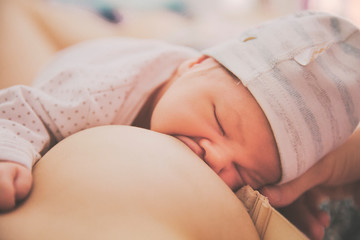 lifestyle photo newborn one month baby with close eyes eating moms brest