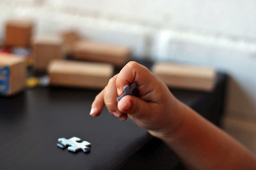 Kid playing puzzle at a black table.