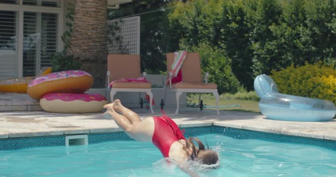 beautiful young woman diving in swimming pool on warm summer day splashing in cool water enjoying summertime wearing red bikini 4k footage