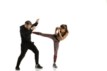 Man in black outfit and athletic caucasian woman fighting on white studio background. Women's...