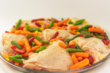 Bits of the raw chicken with vegetables. Сhicken thighs with pepper, baby carrot, green beans and spice waiting for when it to be roasted. Healthy quick lunch or a dinner for family