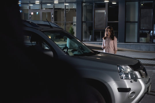 Scared Woman Near Car In Parking Lot At Night