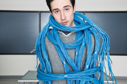 Portrait of technician wrapped in cat 5 cable in computer server room