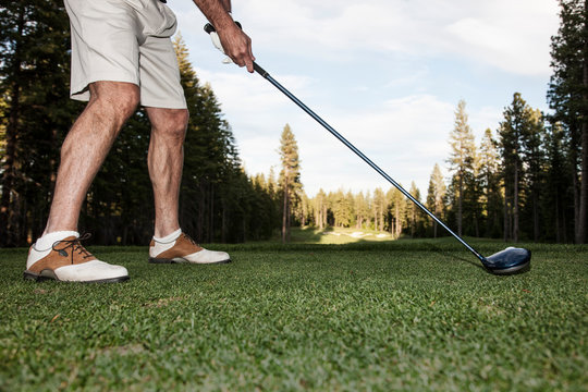 Low section of golfer teeing off golf ball