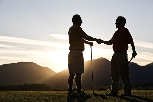 Side View Of Senior Golfers Shaking Hands On Golf Course