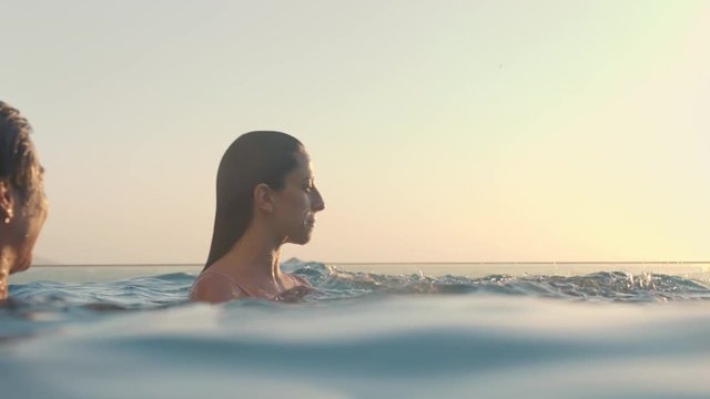 group of friends in swimming pool splashing playfully enjoying summer vacation having fun celebrating summertime at sunset 4k
