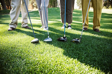 Low section of golfers standing with golf club