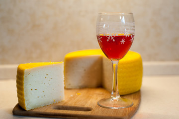 Minimalistic shot of a yellow notched cheese head and a glass of red wine on a bamboo stand