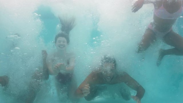 friends jumping in swimming pool underwater having fun celebrating summer vacation together group of teenagers enjoying pool party spring break celebration 4k