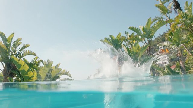 young man jumping in swimming pool in having fun summer vacation enjoying swim at luxury hotel resort on warm sunny day mediterranean travel 4k