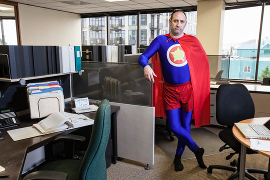 Portrait of mature businessman in super hero costume standing in office