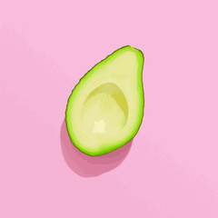 Avocado half on pink background, flat lay