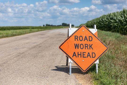 Road work ahead sign on barricade on rural country asphalt road