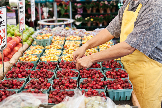 Midsection of man arranging boxes of fresh red cherries in market