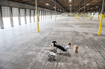 Architect relaxing on chair in warehouse