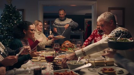 family christmas dinner man cutting turkey serving delicious meal at festive celebration people sitting at table enjoying delicious feast celebrating holiday at home 4k footage