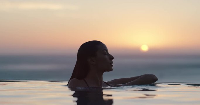 woman relaxing in swimming pool at luxury hotel spa enjoying beautiful golden sunset view of ocean mediterranean travel holiday resort female silhouette 4k