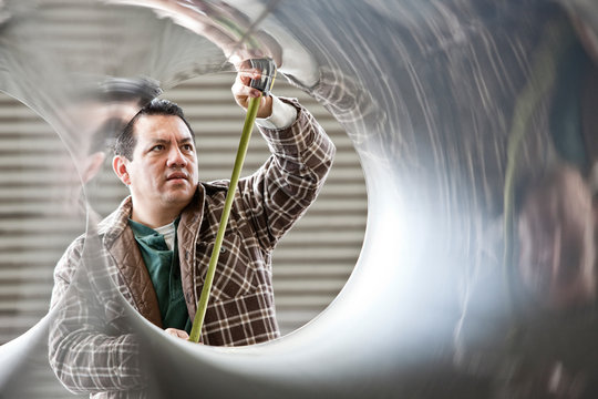 Worker measuring diameter of pipe in factory